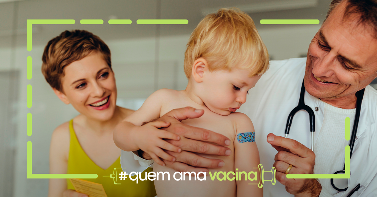 Médico segurando uma criança vacinada e mãe sorrindo